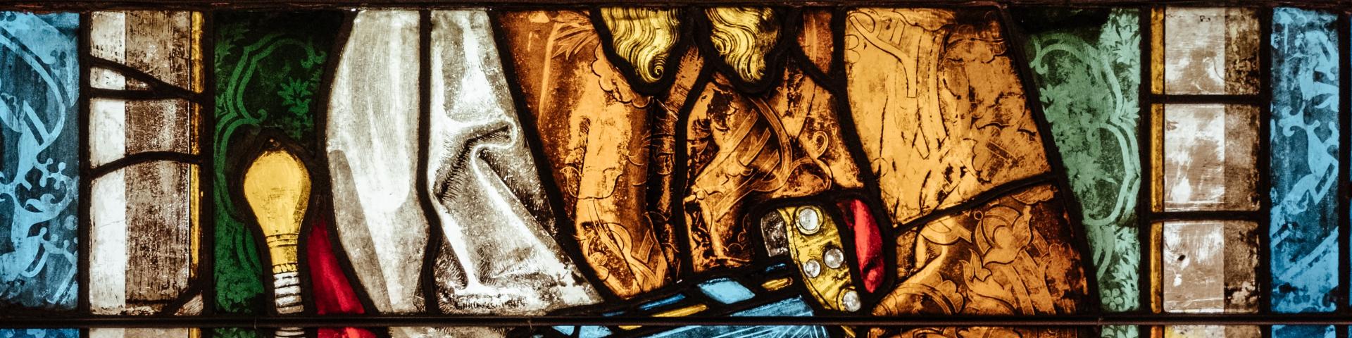 close-up of a stained glass window: a man holding a book