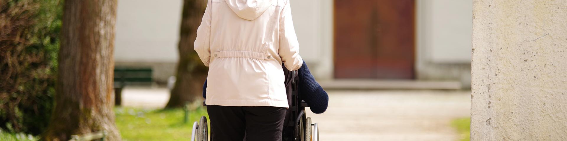 Woman pushes person in wheelchair toward church