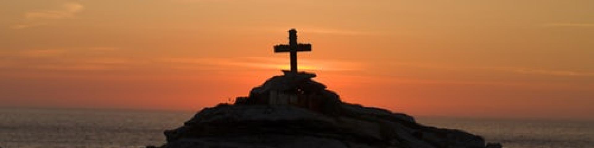 Cross on a hill with a sunset in the background