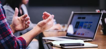 Person with computer talking at a meeting 