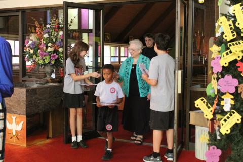 A person who is blind walking out of a Church with other parishioners