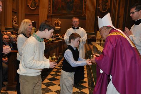 A person with down syndrome giving the gifts to a bishop