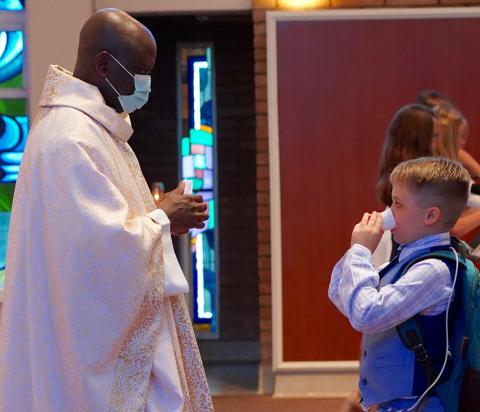 Carson receiving a piece of the Eucharist dissolved in a cup