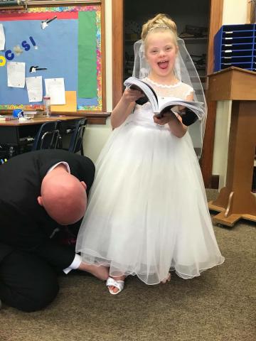 Raylee smiling at the camera in her first communion dress with her first communion book