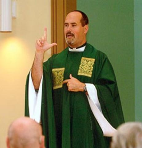 Father Mike Depcik signing as he celebrates Mass