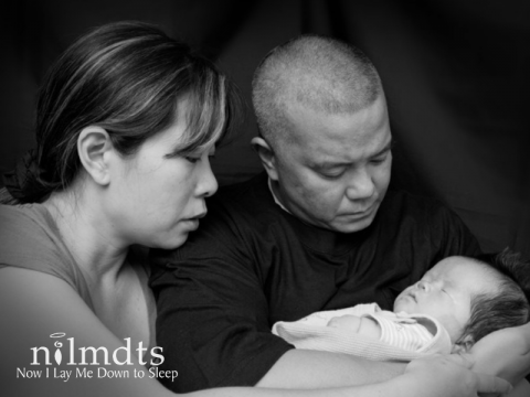 Black and white photo of a father and mother holding and looking at their infant child.