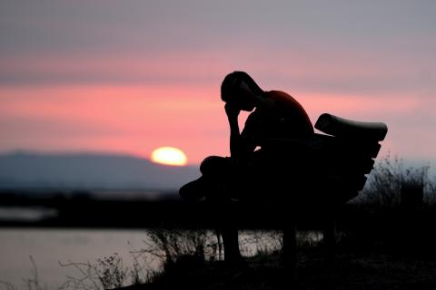 Person sitting on bench with their head down 