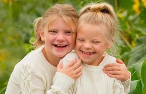 The Reffett sister smiling together in a field of flowers 