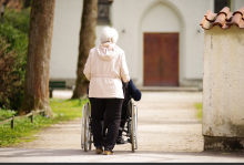 Woman pushes person in wheelchair toward church