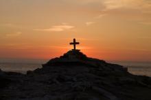 Cross on a hill with a sunset in the background