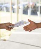 Picture of one person handing another person a bulletin 